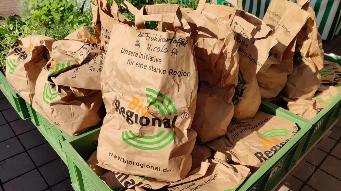 Braune Papiertüten mit Frühkartoffeln am Wochenmarkt in Neuburg