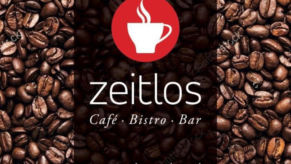cafe-zeitlos-logo-weisse-kaffeetasse-auf-rotem-grund-mit-kaffee-im-hintergrund