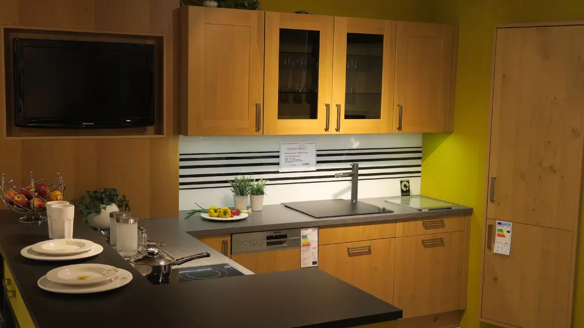 kueche-mit-fernseher-spuelmaschine-und-kochfeld-in-gruen-holzfarben