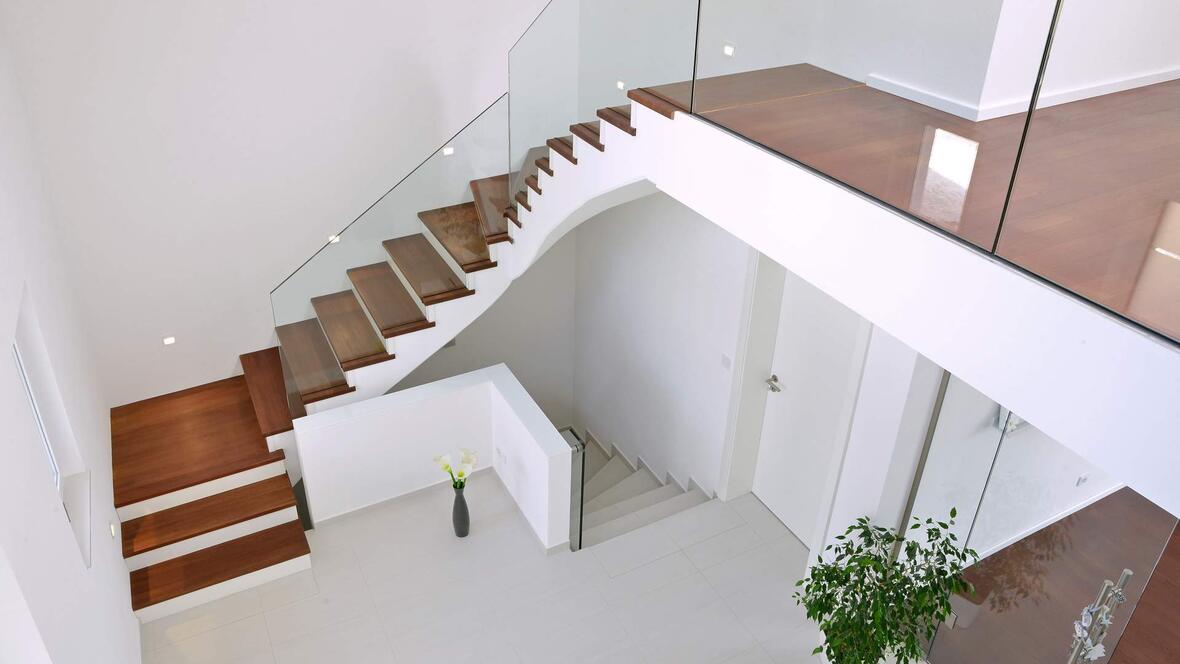 treppenhaus-mit-glasabtrennung-und-dunkelbraunen-treppenstufen-aus-holz