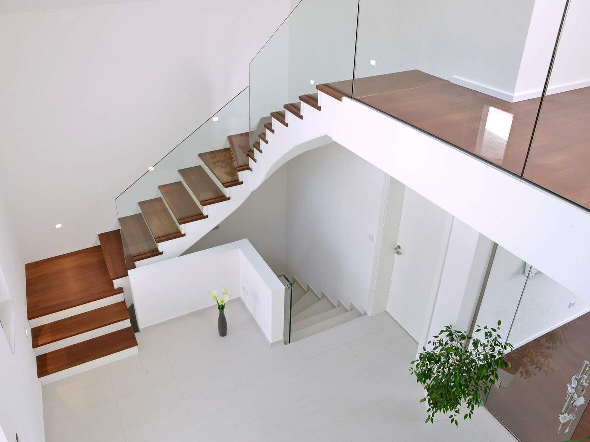 treppenhaus-mit-glasabtrennung-und-dunkelbraunen-treppenstufen-aus-holz