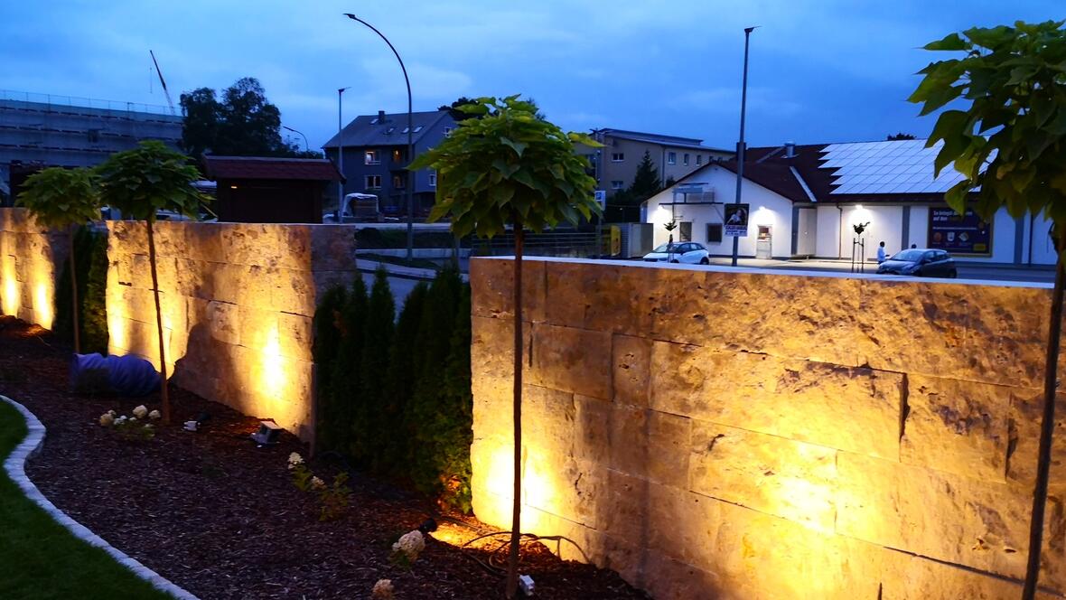 Umgestaltung (Einfassungen,Terrasse, Natursteinmauer, Bepflanzung, Rollrasen, Zaun, Heckenelemente) beleuchtet bei Nacht